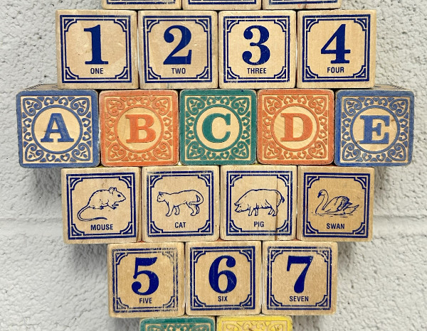 Wooden blocks displaying numbers 1-7, letters A-E, and illustrations of a mouse, cat, pig, and swan.